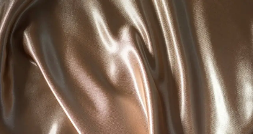 Close up view of nude panne satin fabric showing its glossy and smooth surface texture