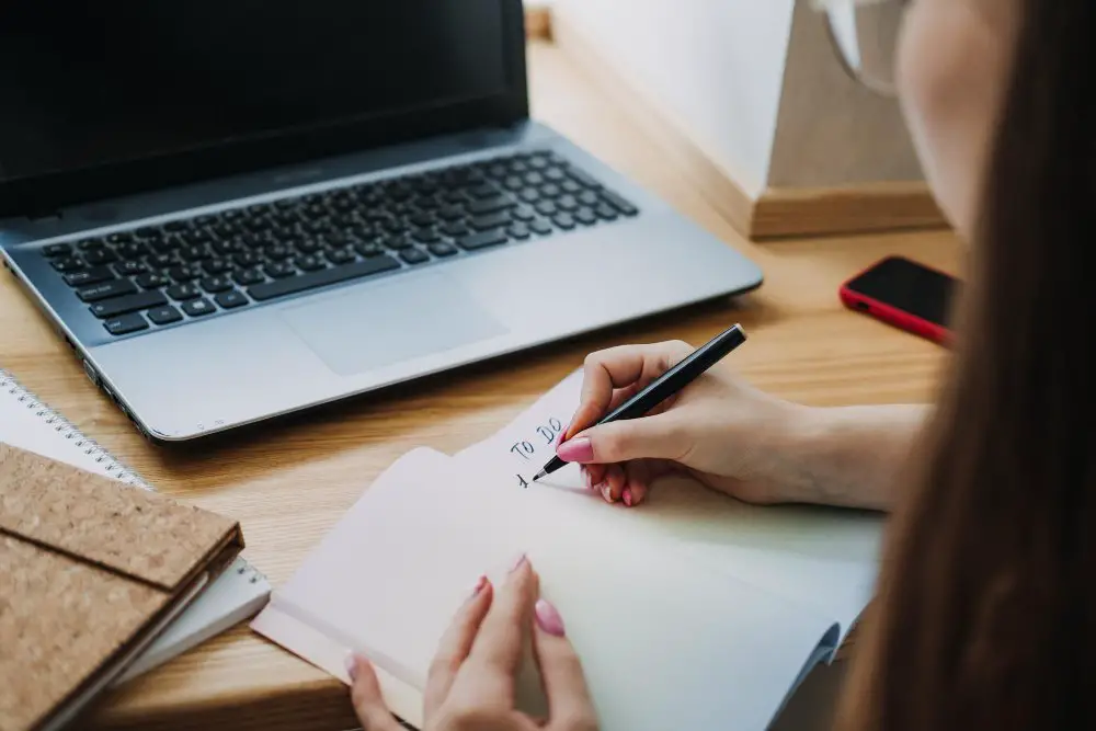 Person writing a pre shopping checklist for junior bridesmaid dress planning at a desk