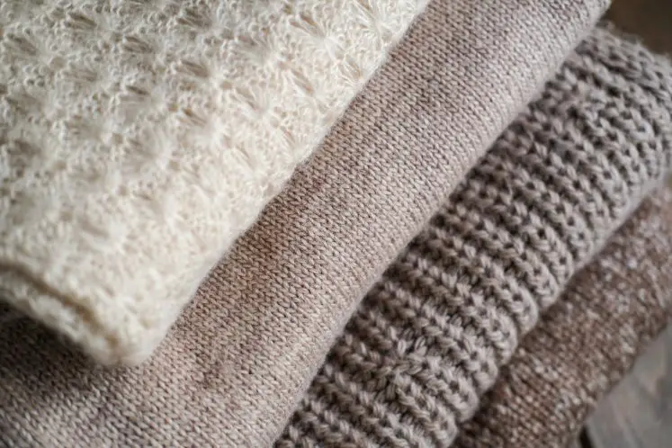 Folded alpaca wool garments showing different textures and knit styles