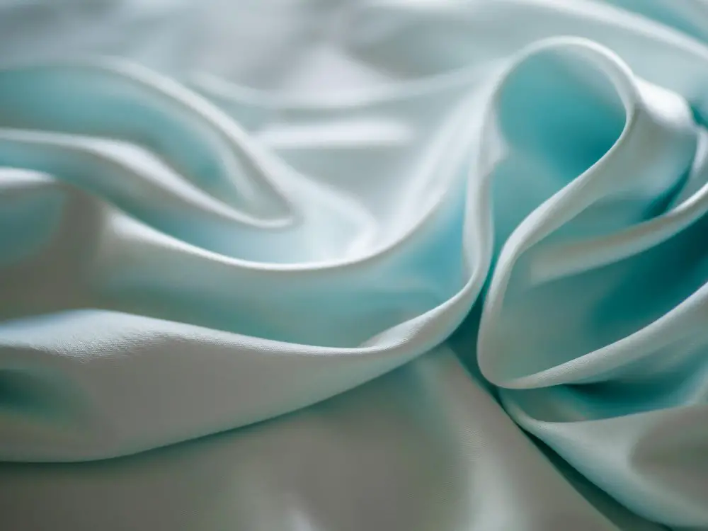 Soft light blue polyester satin fabric laid in elegant folds