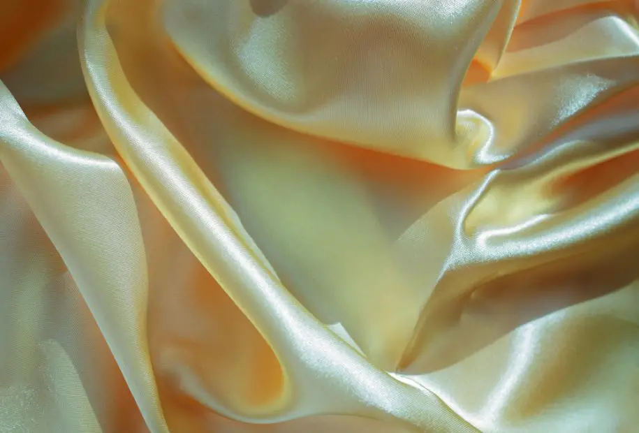 Yellow satin acetate fabric showcasing shiny folds representing the evolution and history of acetate textiles