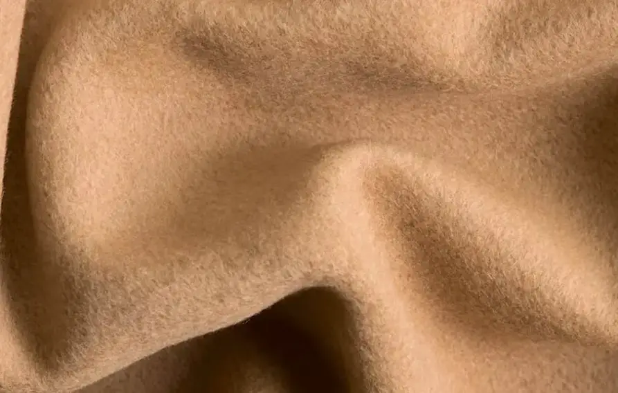 Close up of camel wool fabric showing fine fibers and warm natural brown color