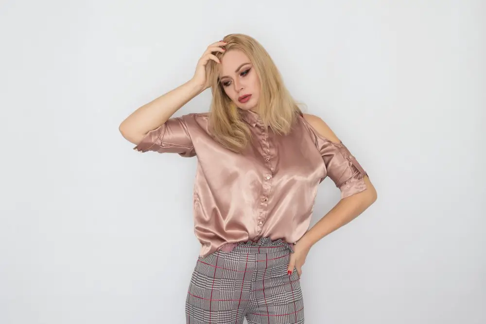 Woman wearing a blush Monroe satin blouse with a smooth finish and subtle sheen