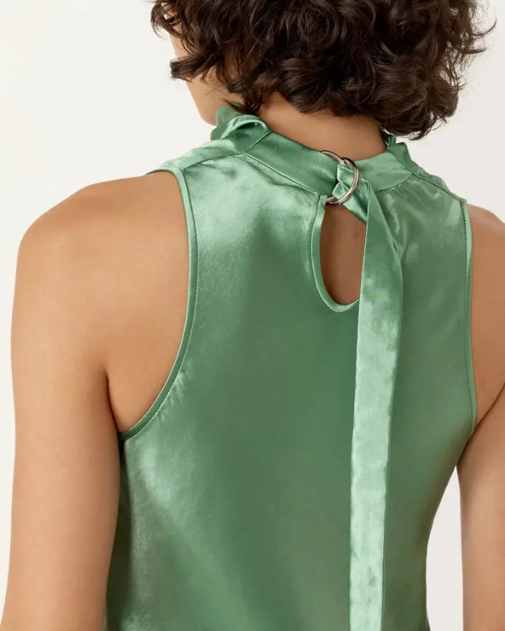 Back view of a woman wearing a green satin acetate top with a tied neckline showing how acetate is used in fashion garments