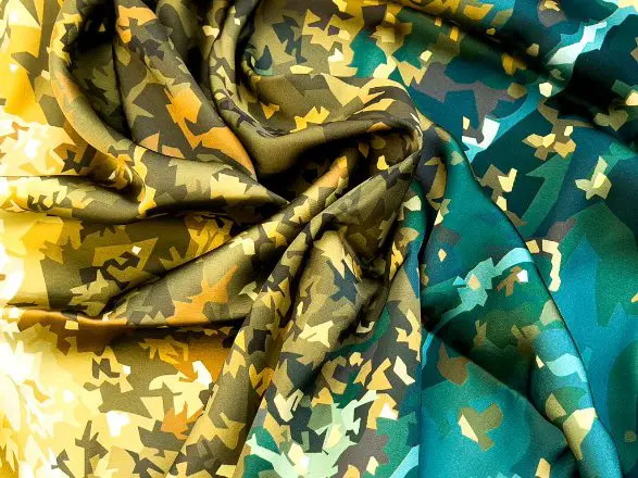 Multicolored baronet satin fabric with a camouflage inspired pattern draped in soft folds. Credit: Feline Malaysia