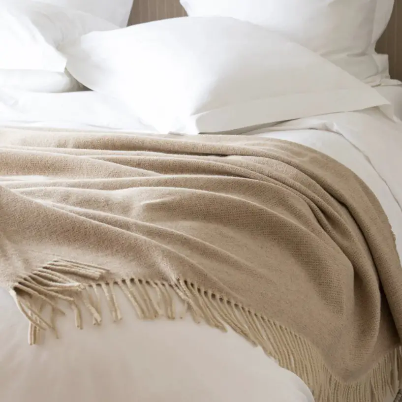 Lambswool throw blanket draped over a bed showing softness and warmth