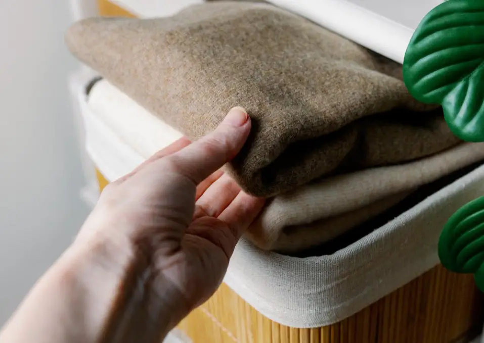 Hand lifting folded merino wool clothing from a storage shelf