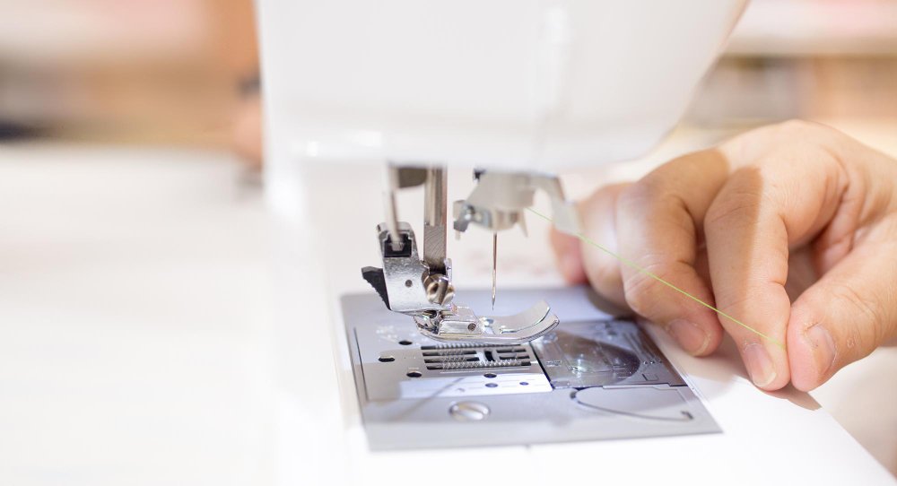 Close up of a sewing machine needle and presser foot preparing to stitch delicate fabric