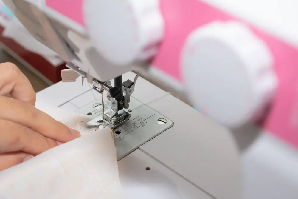 Close up of sewing machine stitching satin blend fabric