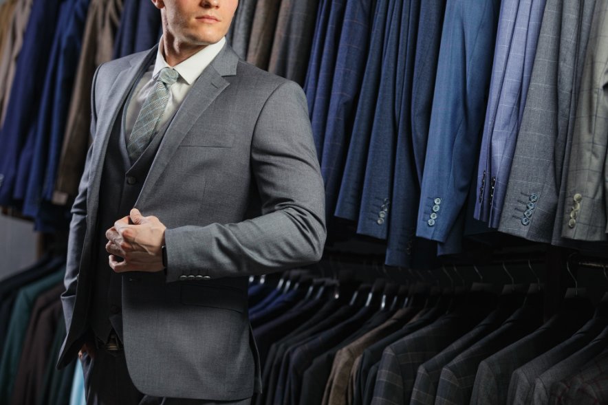 Man wearing a wool sharkskin suit while browsing suit jackets in a store, illustrating how to choose quality sharkskin fabric