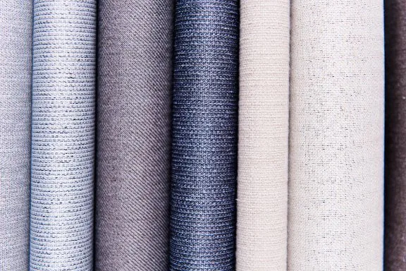 Close up of multiple sharkskin fabric swatches in neutral tones showing texture and weave detail