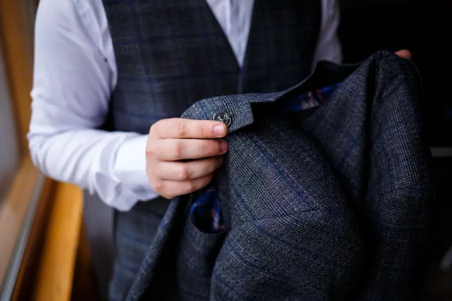 Man inspecting a wool suit jacket showing tailoring details and fabric quality