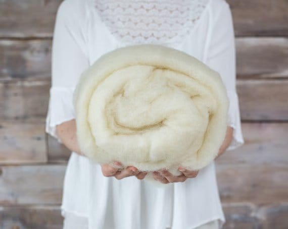 Traditional wool batting held in hands showing natural fibers used historically for insulation