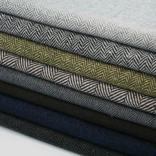 Stack of folded herringbone wool fabrics in different colors and textures