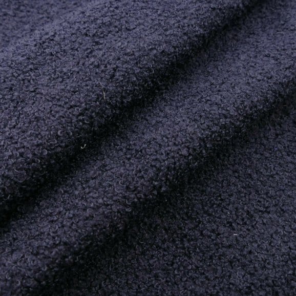 Close up of luxury wool bouclé fabric showing dense loops, soft texture, and refined finish