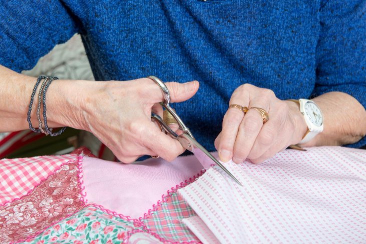 Hands cutting fabric with scissors while sewing wool Voltaire material