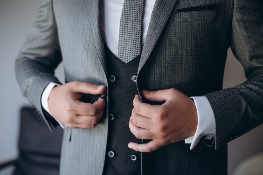 Man adjusting a wool sharkskin suit jacket and waistcoat, showcasing elegant styling and fit