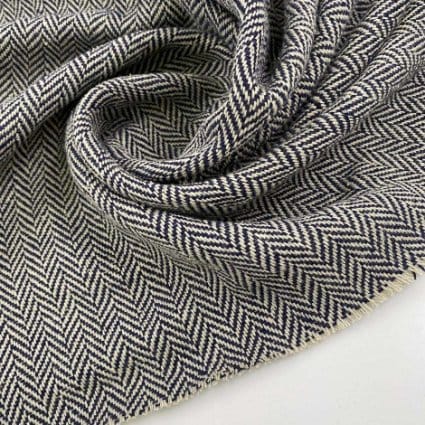 Traditional herringbone wool fabric showing classic zigzag pattern and heritage texture