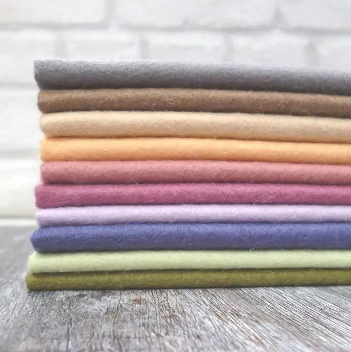 Stacked wool fabric bolts in various colors representing places to buy wool challis fabric