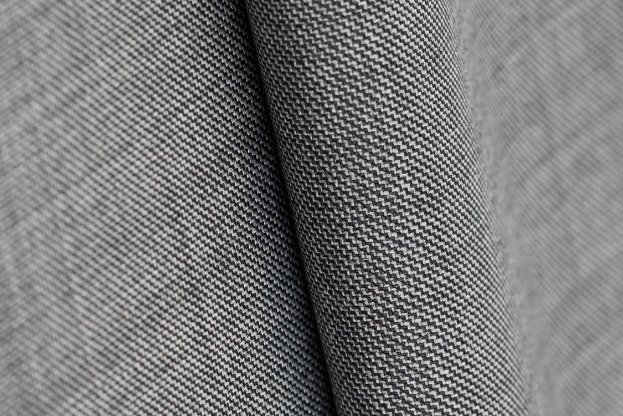 Close up of wool sharkskin fabric showing a fine twill weave and subtle two tone texture.