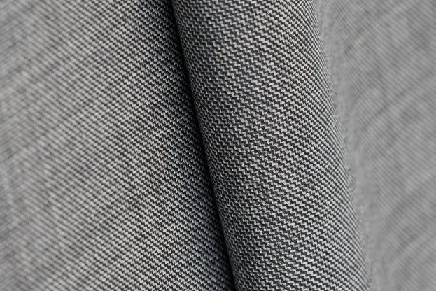 Close up of wool sharkskin fabric showing a fine twill weave and subtle two tone texture.