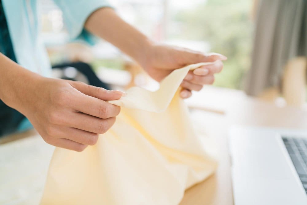 Hands holding sheer chiffon fabric to examine transparency and texture
