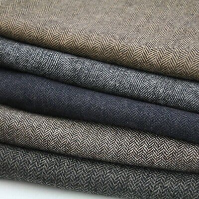 Folded herringbone wool fabric showing textured weave in neutral tones