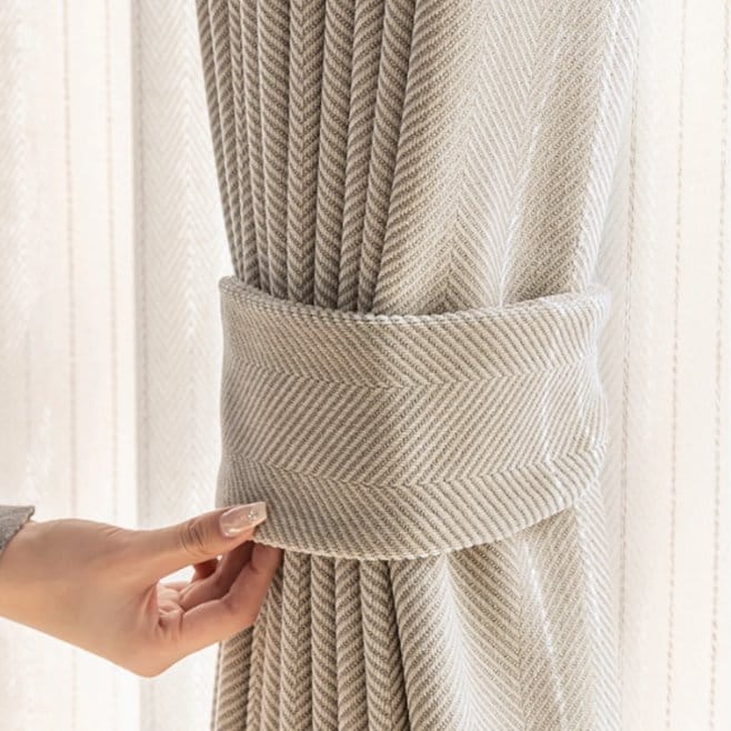 Herringbone wool curtain tied back with fabric holder in softly lit room