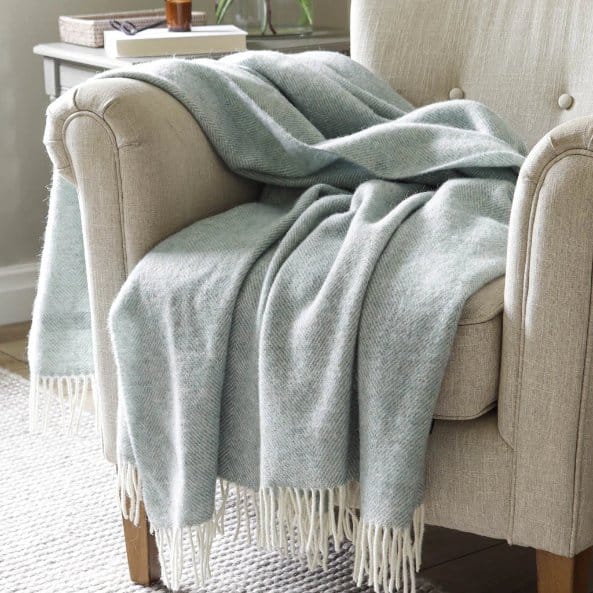 Herringbone wool throw blanket draped over armchair in cozy living room