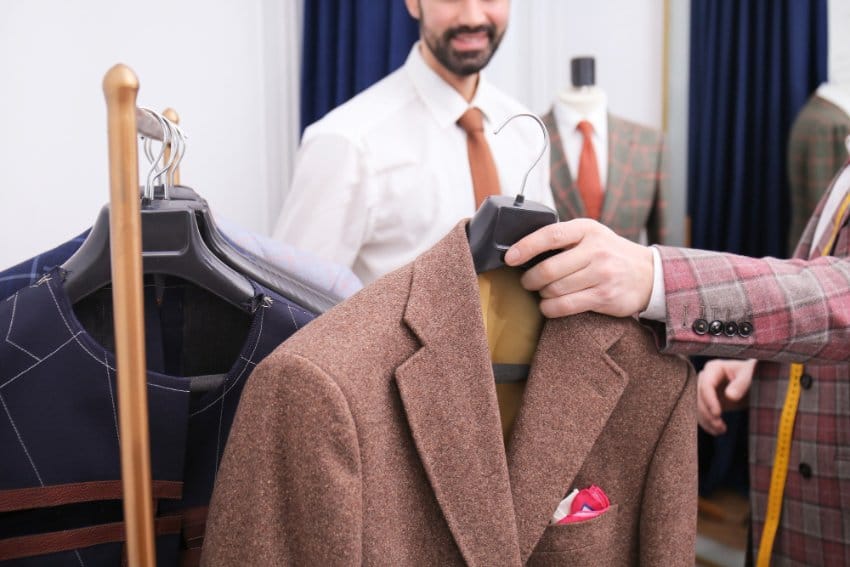 Tailor holding melton wool coats showing quality, thickness, and fabric selection for buying melton wool