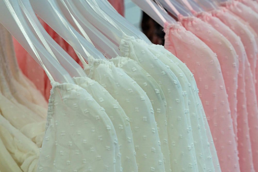 Pastel nylon chiffon fabrics in soft pink and mint colors hanging on clear hangers showing lightweight drape and texture