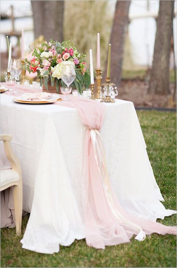Outdoor table decorated with flowing pink chiffon fabric draped as soft romantic event styling