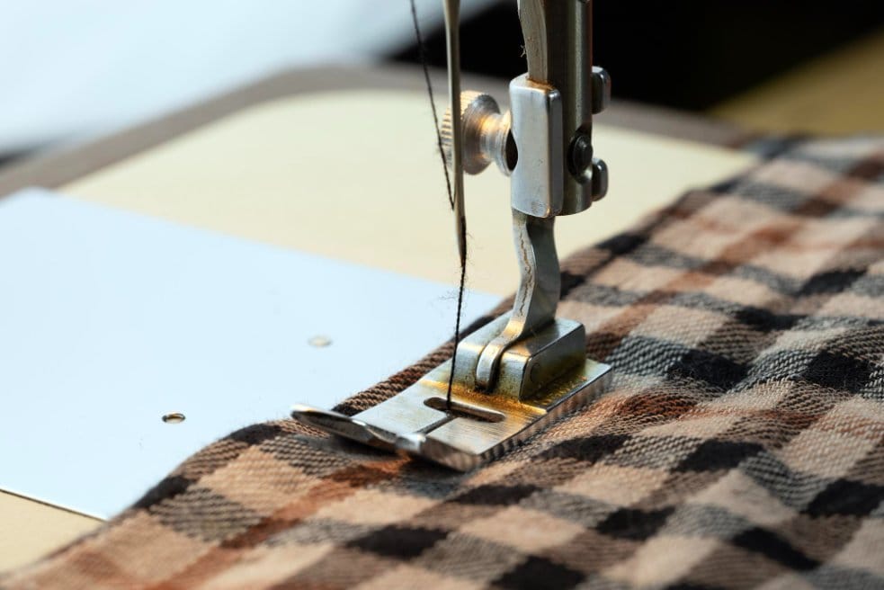 Sewing machine stitching herringbone wool fabric during garment construction