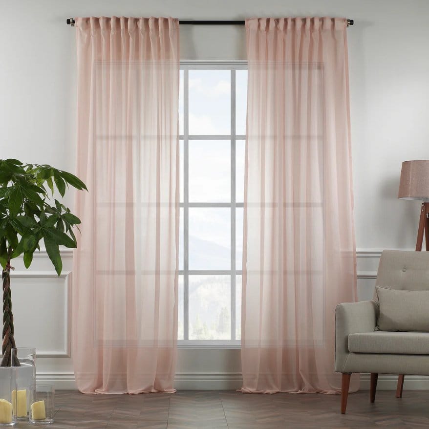 Sheer silk chiffon curtains hanging by a window allowing soft filtered light