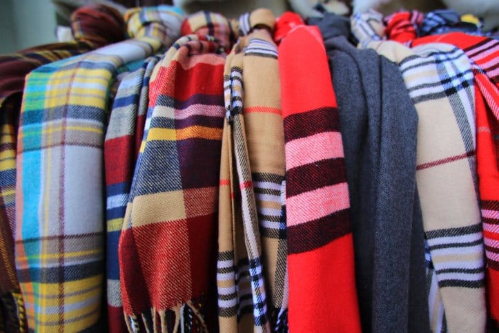 Stack of folded tartan wool fabrics in various colors and patterns