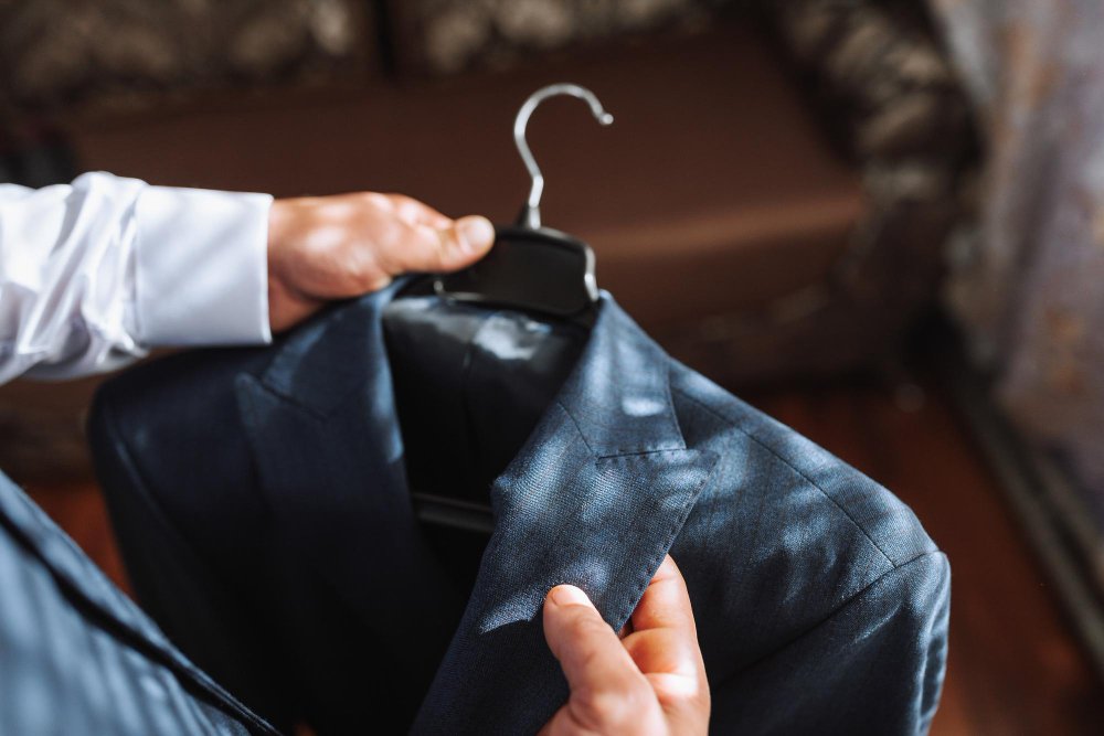 Hands holding and inspecting barathea garment for proper care and maintenance