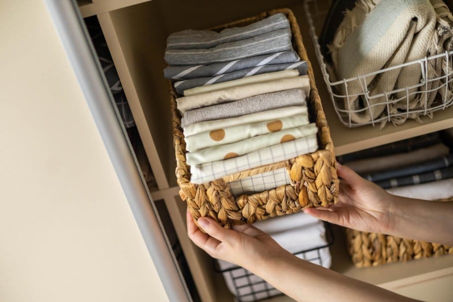Folded wool broadcloth fabric stored neatly in a basket on shelving
