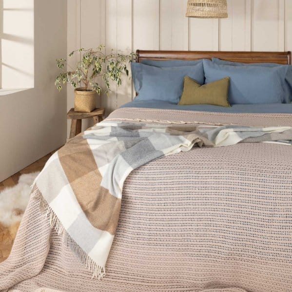 Wool jersey throw blanket styled on a bed in a light and cozy bedroom