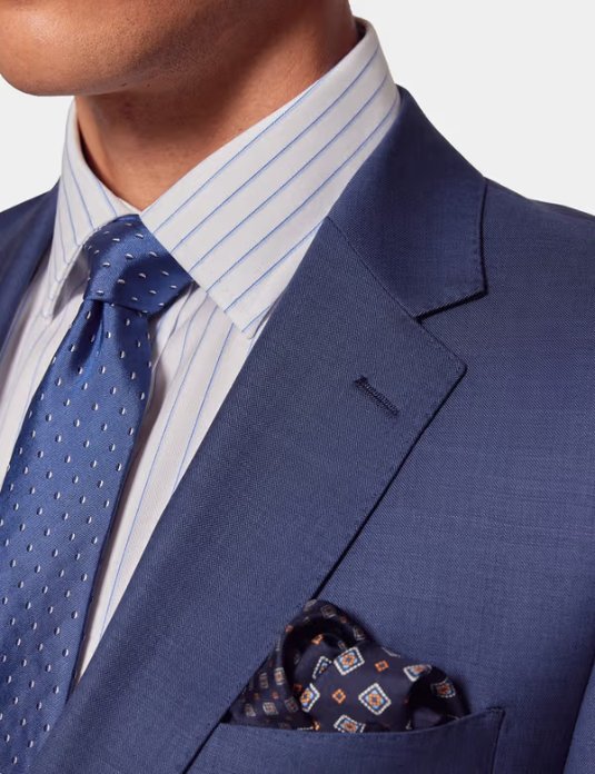 Close up of a navy wool sharkskin business suit showing lapel, tie, and pocket square detail. Credit: Hawes & Curtis