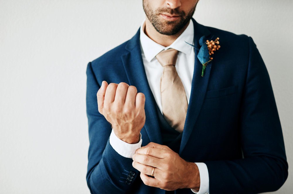 Man adjusting cuff of a wool sharkskin suit styled for a wedding or special occasion