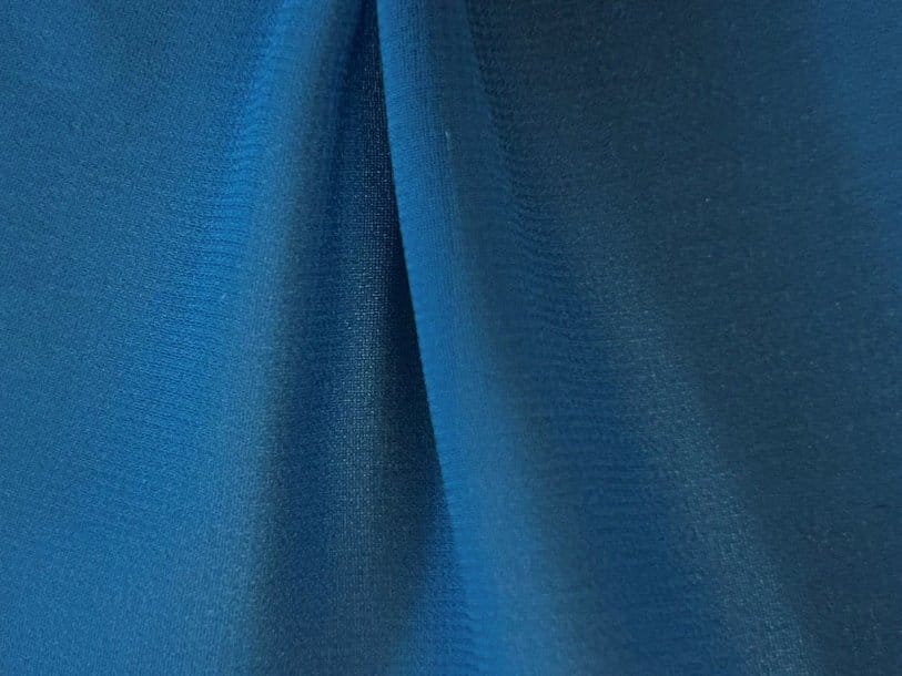 Close up of deep blue polyester chiffon fabric folds showing smooth weave lightweight texture and modern synthetic finish
