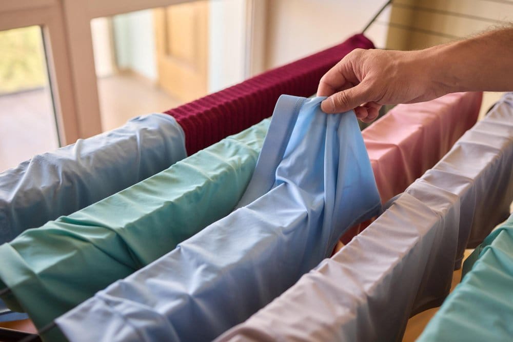 Hand hanging stretch chiffon garments to air dry on a laundry rack