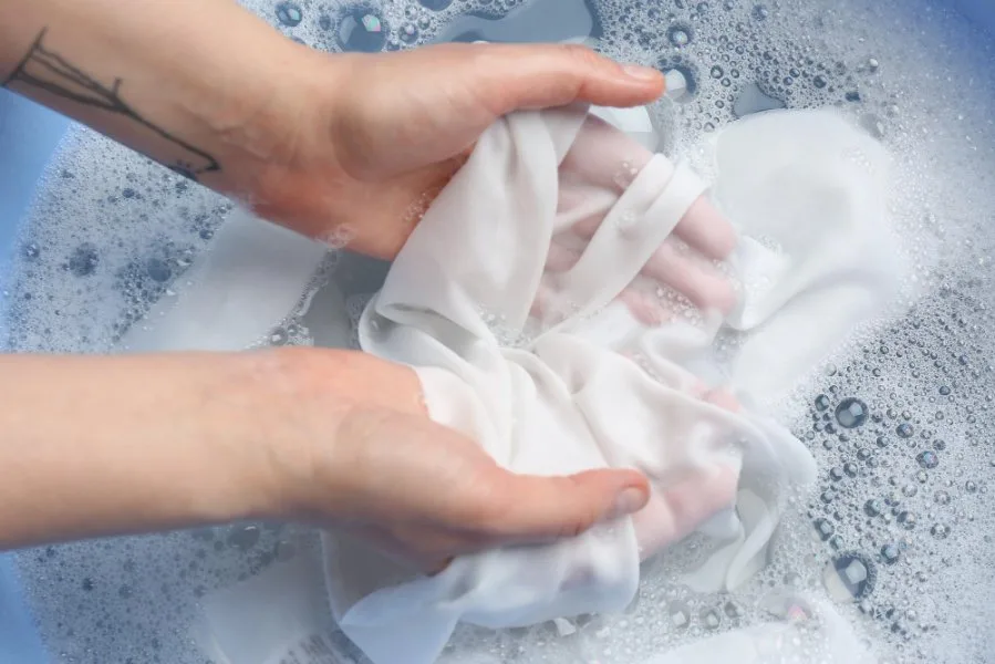Hands gently hand washing sheer georgette chiffon fabric in soapy water