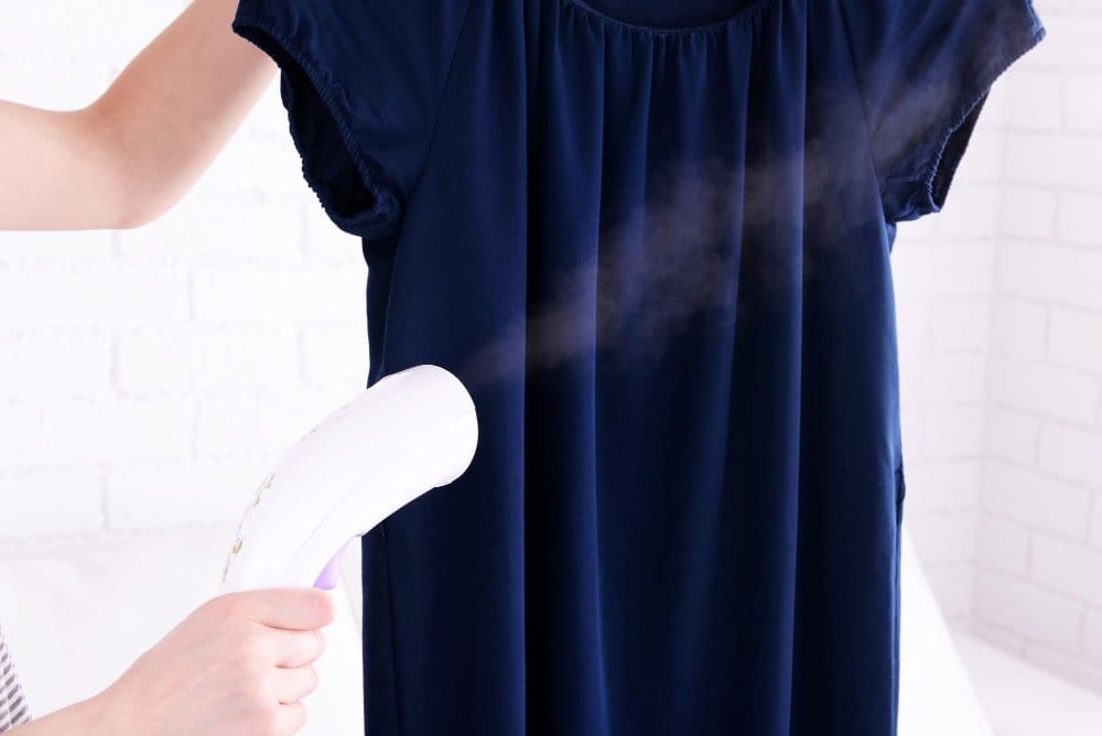 Steaming wrinkles from a navy georgette chiffon dress using a handheld garment steamer