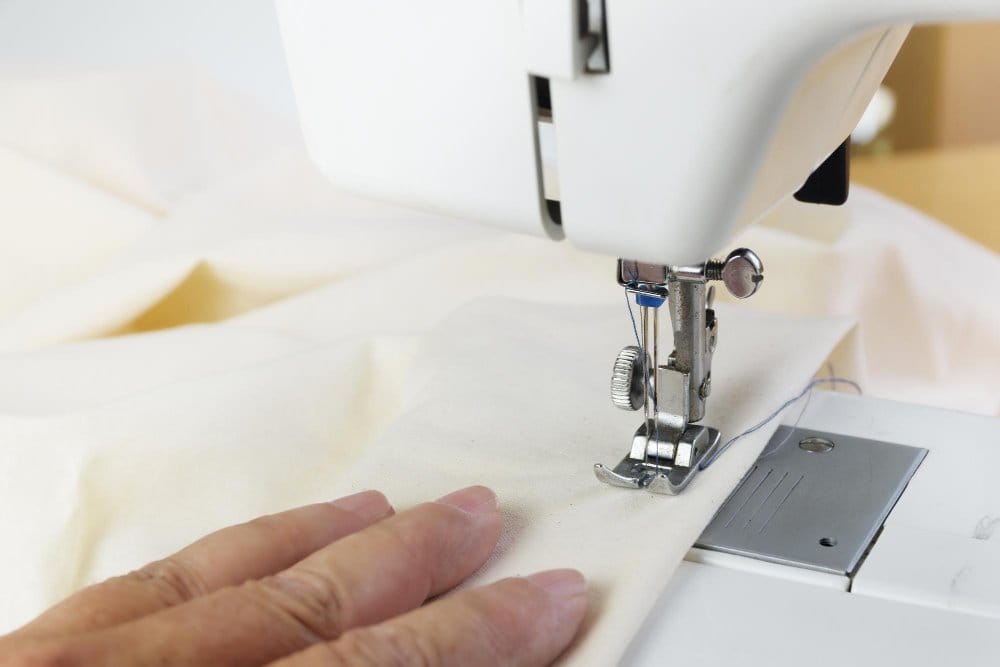 Sewing machine stitching delicate lurex chiffon fabric close up
