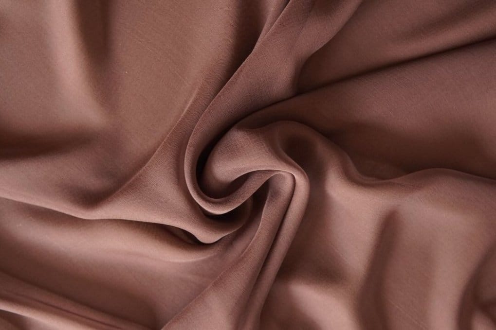 Brown silk crepe chiffon fabric with soft matte texture and elegant fluid drape demonstrating natural luxury fiber
