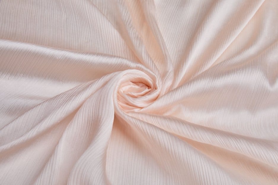 Peach crinkle chiffon fabric arranged in soft flowing folds