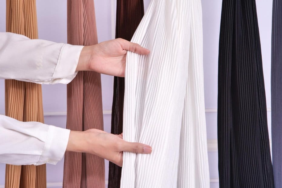 Shopper examining pleated crinkle chiffon panels in various colors