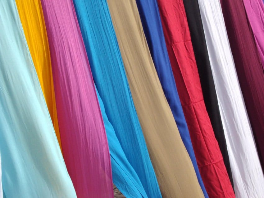 Multiple colorful crepe chiffon fabrics hanging vertically in bright shades showing texture options and color variety for sewing