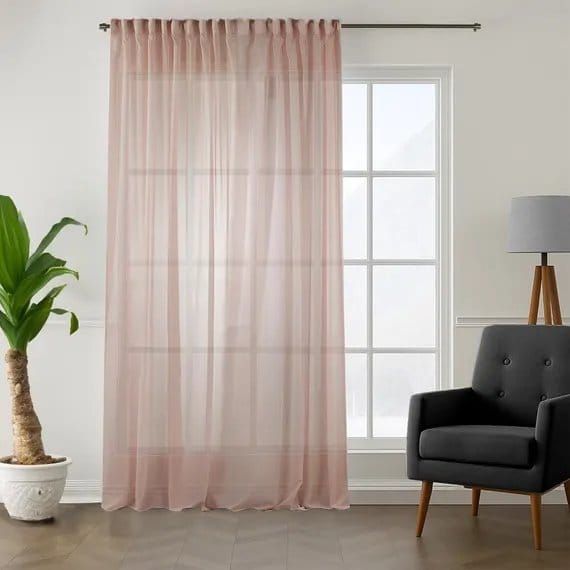 Sheer pink crepe chiffon curtains hanging by window diffusing sunlight and creating soft airy interior decor